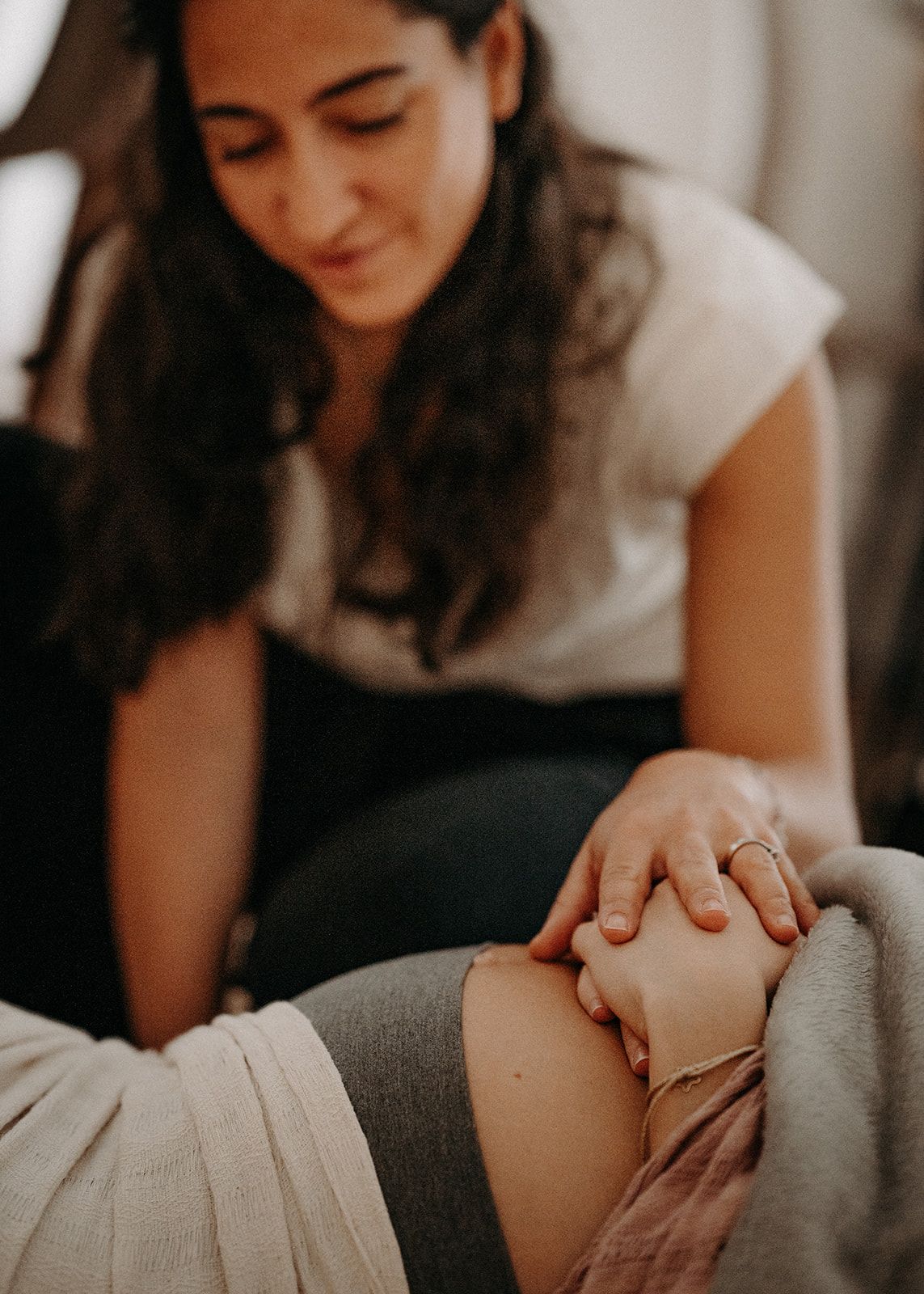 Elsa Uzan, la main posée sur le ventre d'une femme enceinte détendue, pendant une séance HypnoNatal